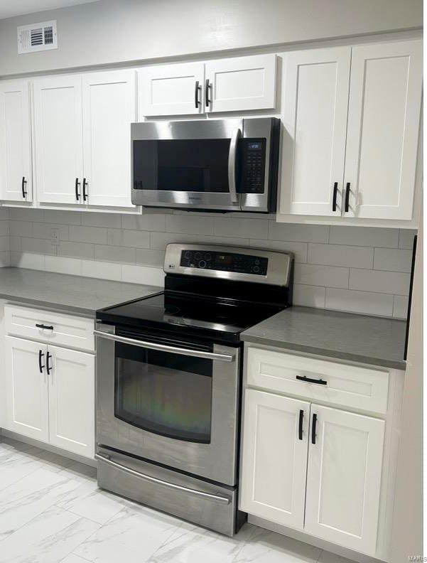 kitchen featuring white cabinets, decorative backsplash, and stainless steel appliances