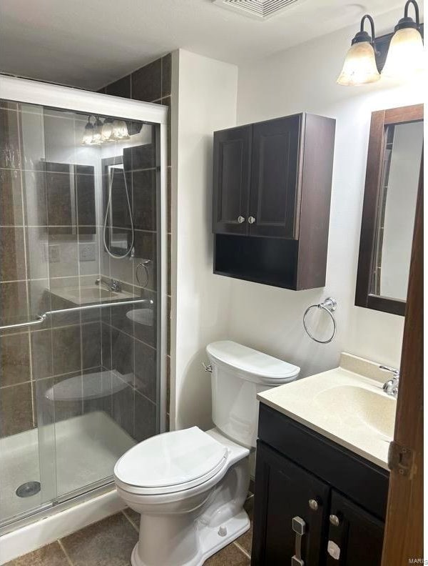 bathroom featuring toilet, vanity, tile patterned floors, and an enclosed shower