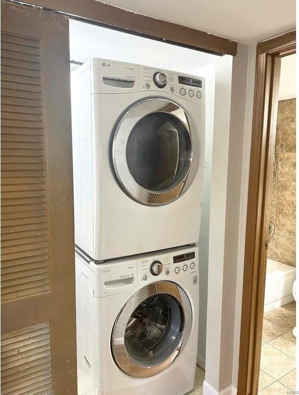 laundry room featuring stacked washer and dryer and light tile patterned flooring