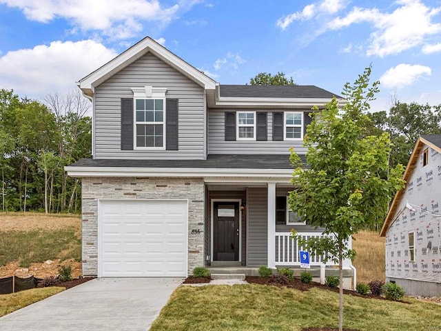 view of front of property with a garage, a front lawn, and covered porch