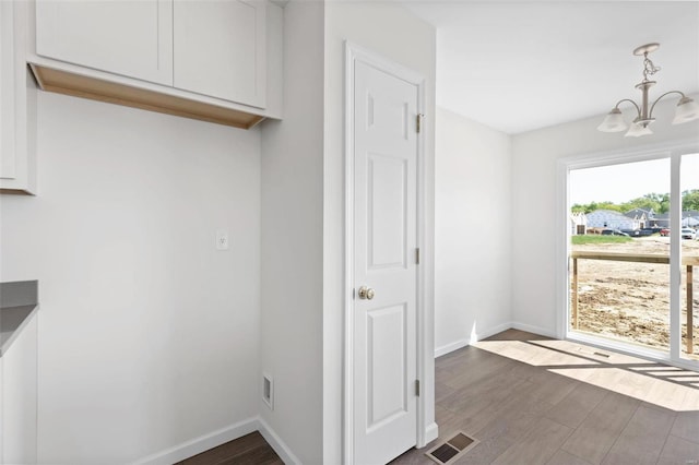 interior space featuring a notable chandelier, dark hardwood / wood-style floors, and white cabinets