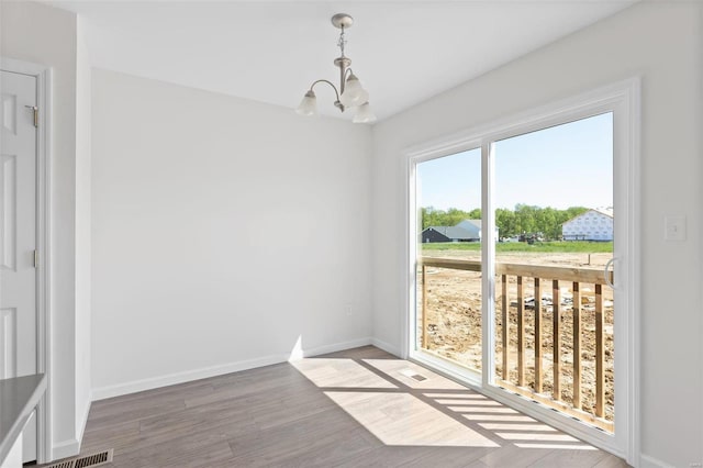 unfurnished dining area with wood-type flooring and an inviting chandelier