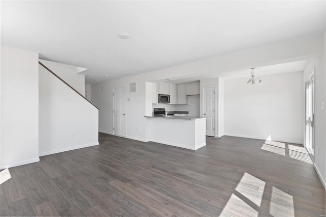 unfurnished living room featuring a chandelier and dark hardwood / wood-style floors