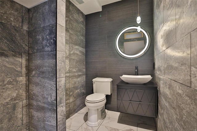 bathroom with vanity, toilet, and tile walls