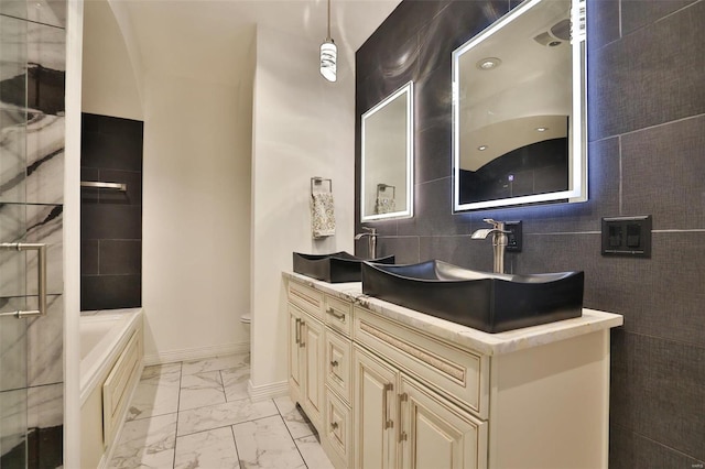 bathroom featuring a bathtub, vanity, tile walls, and toilet