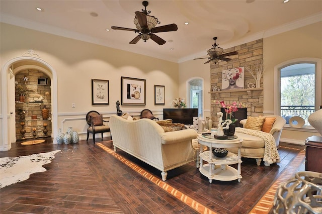 living room with ceiling fan, a fireplace, dark wood-type flooring, and ornamental molding