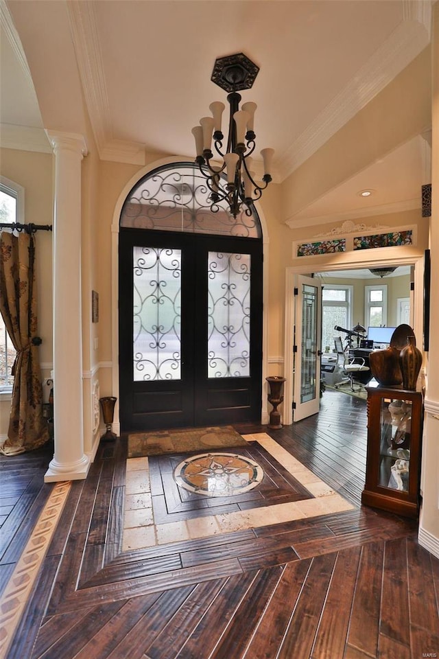 foyer entrance with decorative columns, french doors, ornamental molding, and a notable chandelier