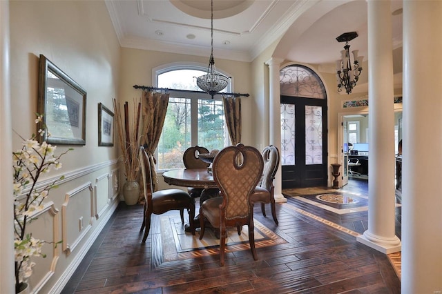 dining space featuring french doors, decorative columns, a tray ceiling, an inviting chandelier, and dark hardwood / wood-style floors