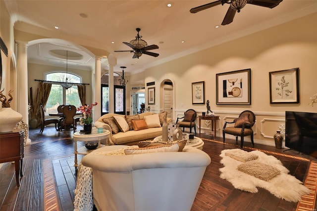 living room with ceiling fan with notable chandelier, decorative columns, dark hardwood / wood-style floors, and crown molding