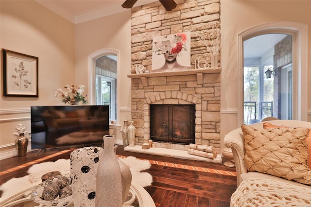 sitting room with a stone fireplace, crown molding, and hardwood / wood-style floors