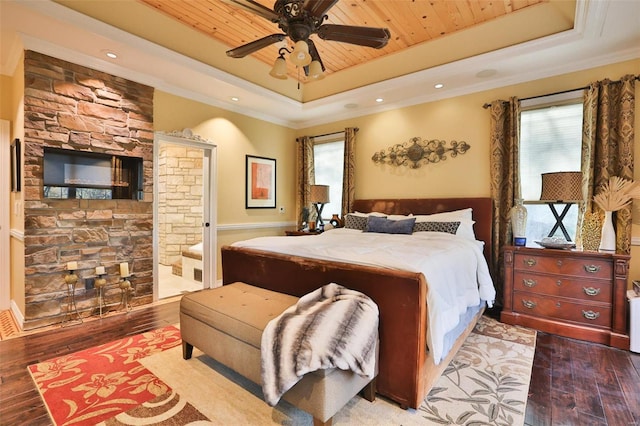 bedroom featuring a tray ceiling, ceiling fan, light hardwood / wood-style floors, and ensuite bathroom