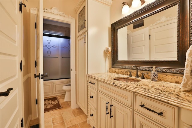 full bathroom featuring vanity, toilet, and shower / bath combination with glass door