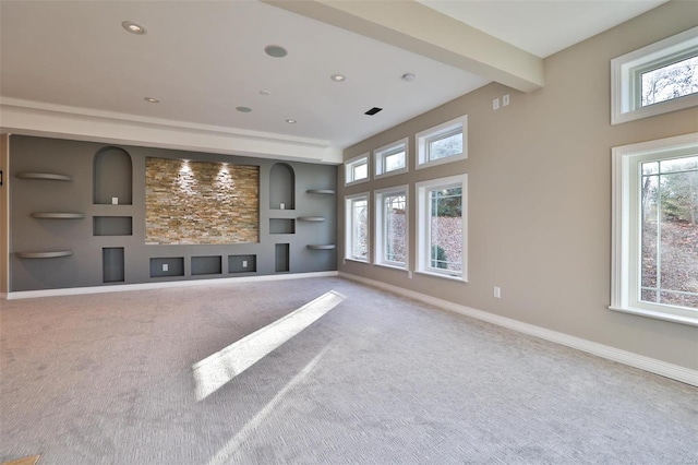 unfurnished living room featuring carpet, beam ceiling, built in features, and a wealth of natural light