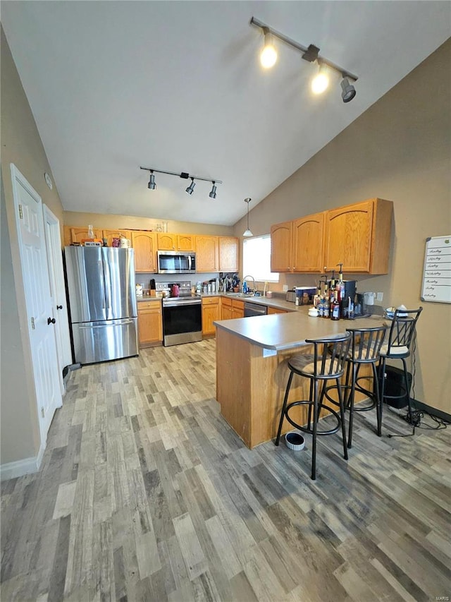 kitchen featuring stainless steel appliances, a kitchen breakfast bar, kitchen peninsula, decorative light fixtures, and lofted ceiling