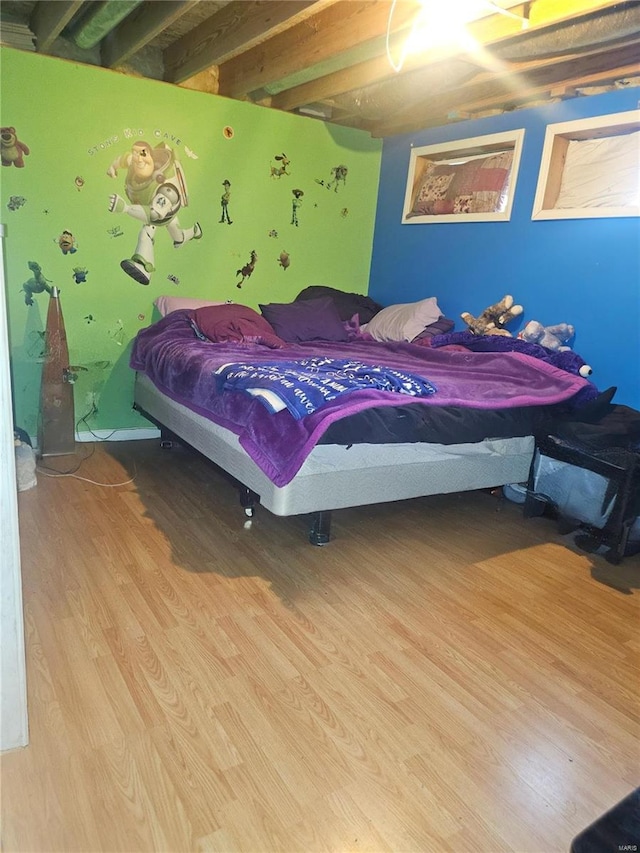 bedroom featuring beam ceiling and light hardwood / wood-style flooring