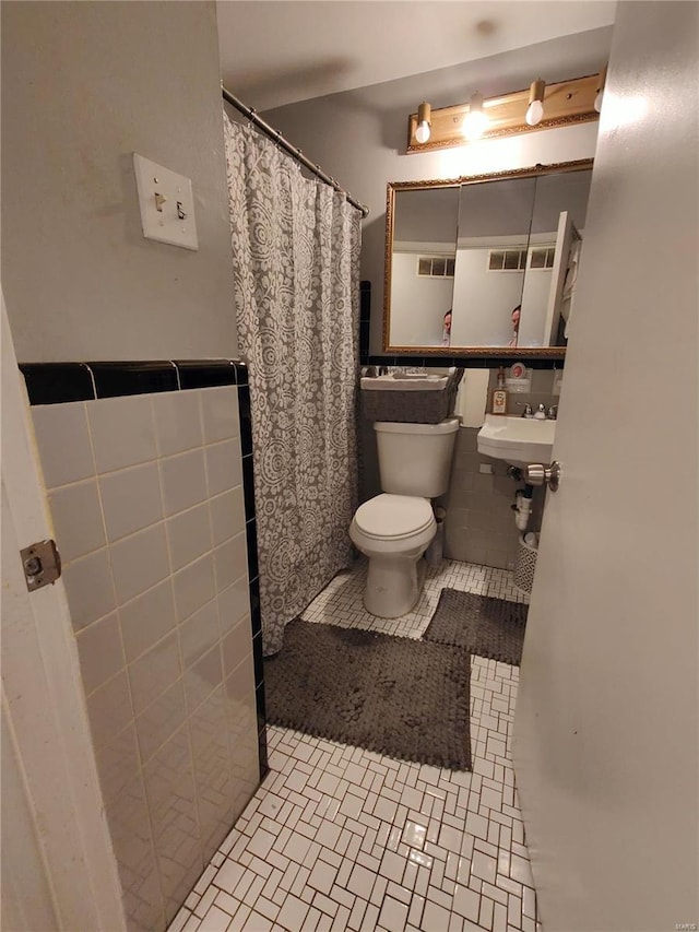 bathroom with tile patterned flooring, toilet, and tile walls