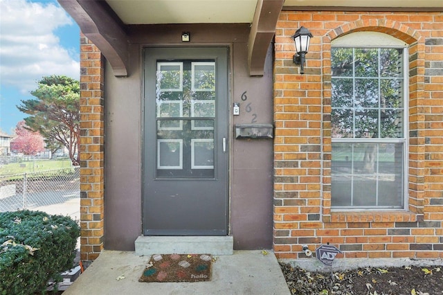 property entrance with brick siding and fence