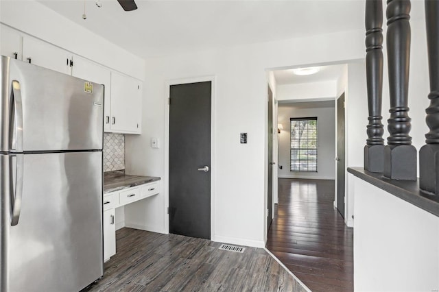 kitchen with dark countertops, dark wood finished floors, freestanding refrigerator, white cabinets, and decorative backsplash