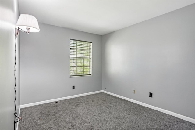 spare room featuring carpet flooring, visible vents, and baseboards