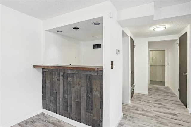 interior space with indoor wet bar, wood finished floors, baseboards, and a textured ceiling