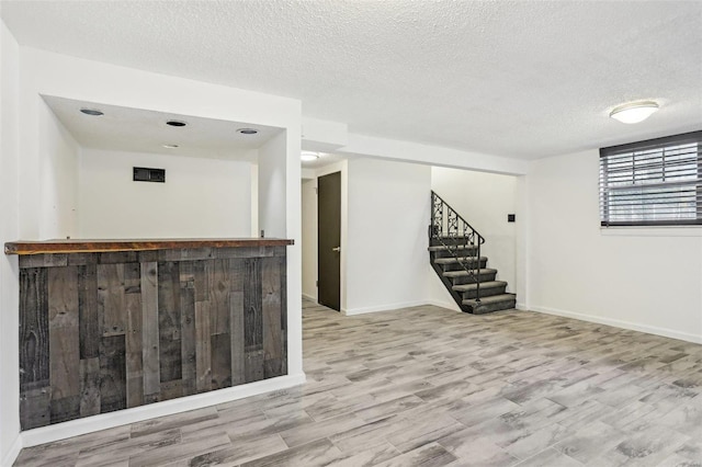 interior space featuring a textured ceiling, wood finished floors, and stairs