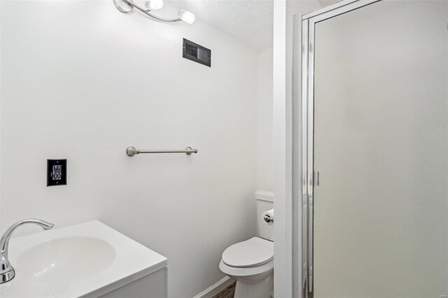 bathroom with visible vents, a shower stall, toilet, and a sink