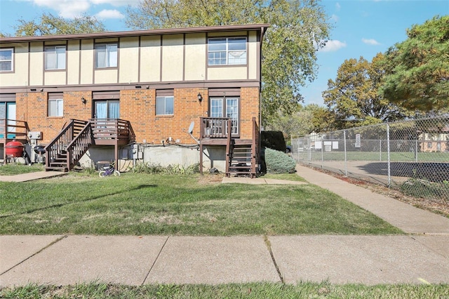 back of property with brick siding, a lawn, and fence