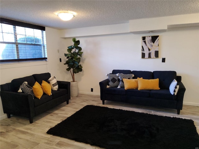 living area with wood finished floors, baseboards, and a textured ceiling