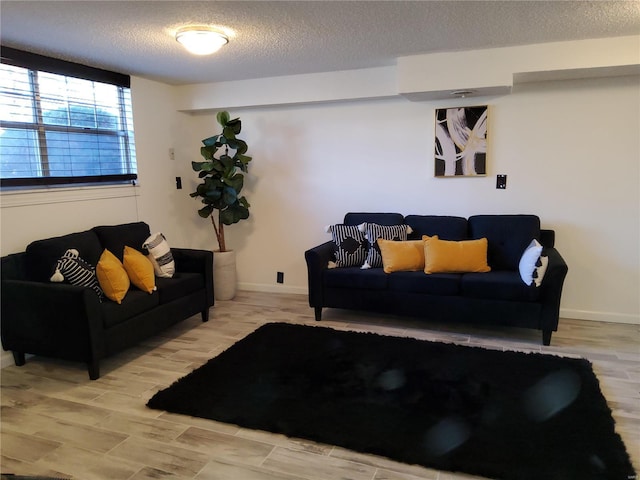 living room with baseboards, a textured ceiling, and wood finished floors