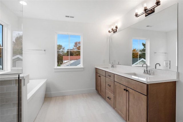 bathroom featuring vanity, tiled tub, and plenty of natural light