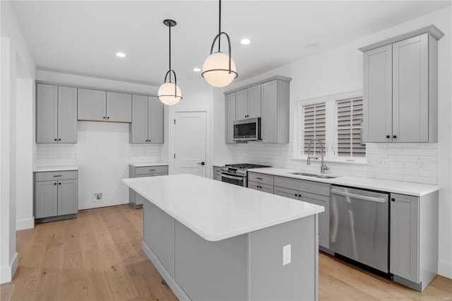 kitchen featuring stainless steel appliances, sink, light hardwood / wood-style flooring, a center island, and pendant lighting