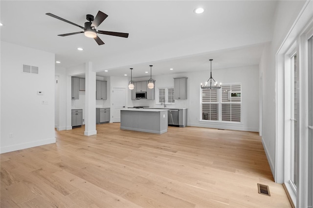 unfurnished living room featuring light wood-type flooring and ceiling fan with notable chandelier