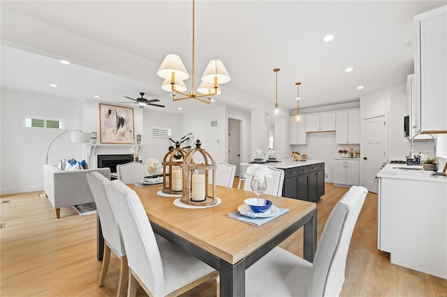 dining area with ceiling fan with notable chandelier and light wood-type flooring