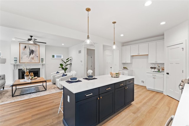 kitchen with a center island, backsplash, pendant lighting, light hardwood / wood-style floors, and white cabinets