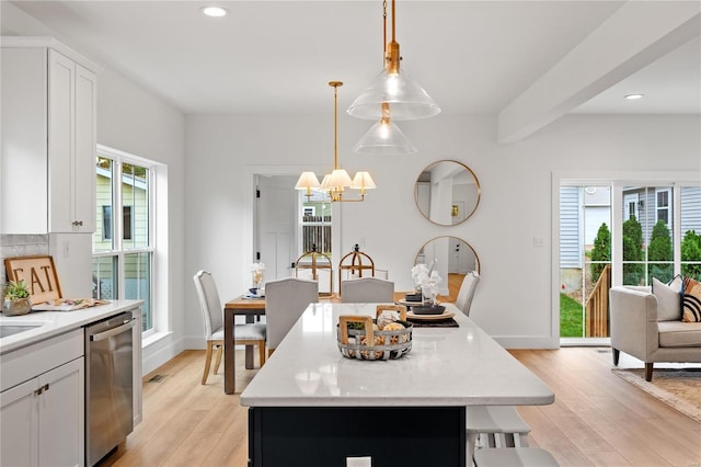 kitchen featuring a center island, light hardwood / wood-style floors, stainless steel dishwasher, and a wealth of natural light