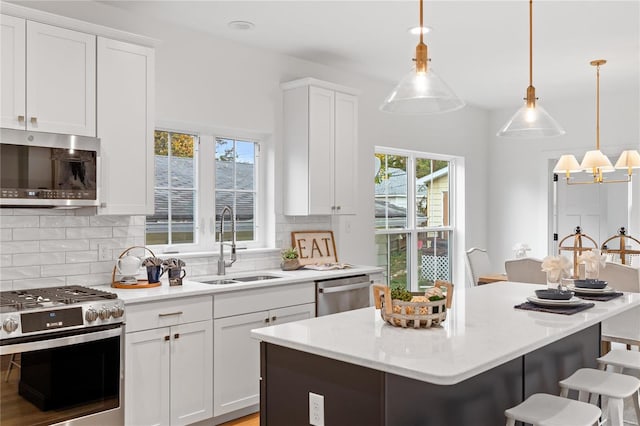 kitchen featuring a breakfast bar area, white cabinetry, hanging light fixtures, and appliances with stainless steel finishes