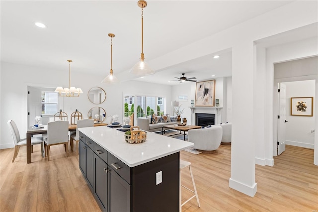 kitchen featuring pendant lighting, ceiling fan with notable chandelier, light hardwood / wood-style floors, and a kitchen island