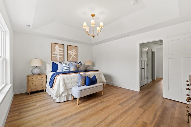 bedroom with a raised ceiling, wood-type flooring, and an inviting chandelier