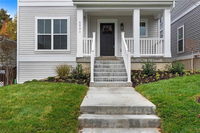 view of exterior entry featuring a porch and a yard