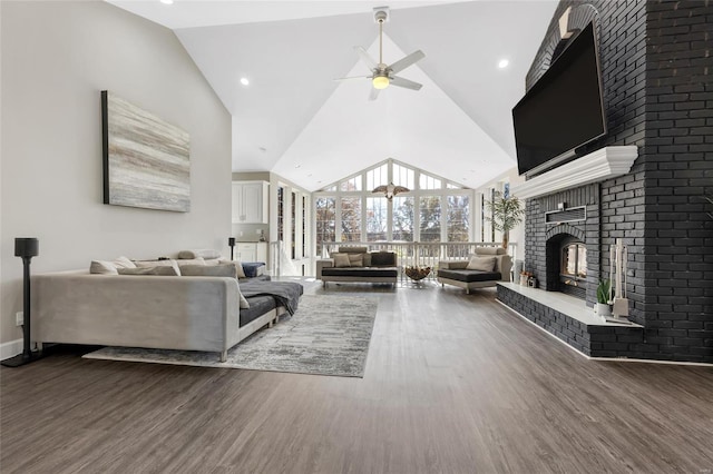 living room featuring dark hardwood / wood-style floors, ceiling fan, high vaulted ceiling, and a brick fireplace