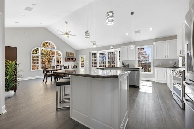 kitchen with stainless steel appliances, a kitchen island, pendant lighting, dark hardwood / wood-style floors, and white cabinetry