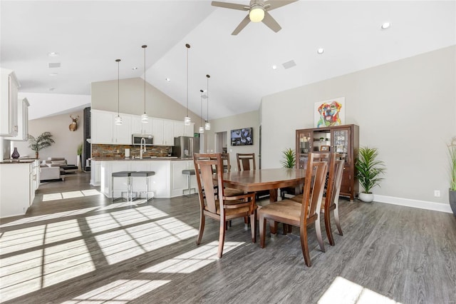 dining room with ceiling fan, dark hardwood / wood-style flooring, and high vaulted ceiling