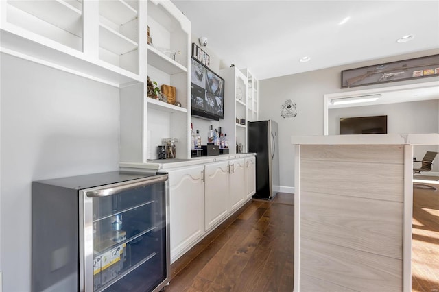 bar with white cabinets, dark hardwood / wood-style floors, beverage cooler, and stainless steel refrigerator