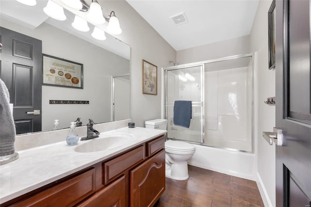 full bathroom featuring hardwood / wood-style floors, vanity, toilet, and shower / bath combination with glass door