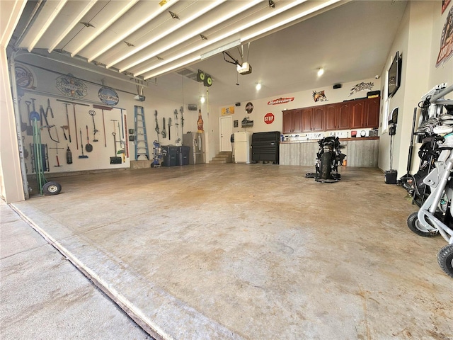 garage featuring stainless steel fridge, a garage door opener, and white refrigerator