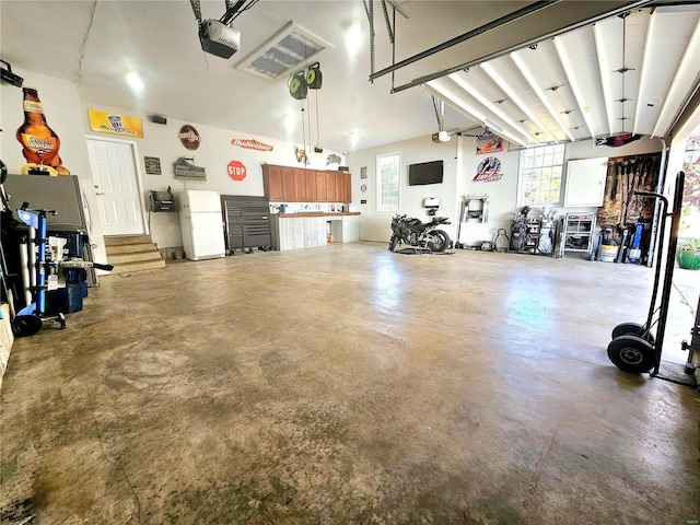 garage featuring white fridge and a garage door opener