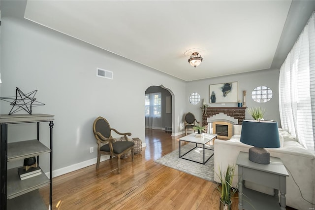 living room with a brick fireplace and wood-type flooring