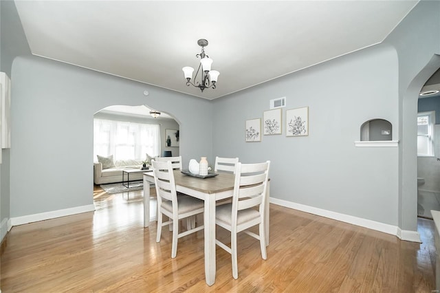 dining space with light hardwood / wood-style floors and a chandelier