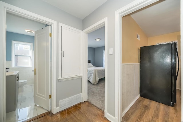 hall featuring light hardwood / wood-style flooring and tile walls