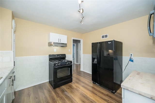 kitchen featuring white cabinetry, black appliances, light stone counters, and wood-type flooring